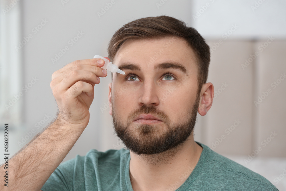 Obraz premium Young man using eye drops on blurred background