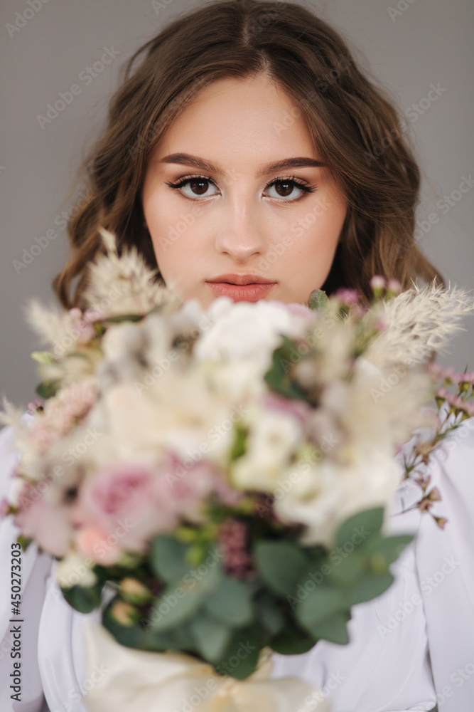 Portrait of young bride with wedding bouquet in front of grey backgound. Studio photophoot Portrait of young bride with wedding bouquet in front of grey backgound. Studio photophoot