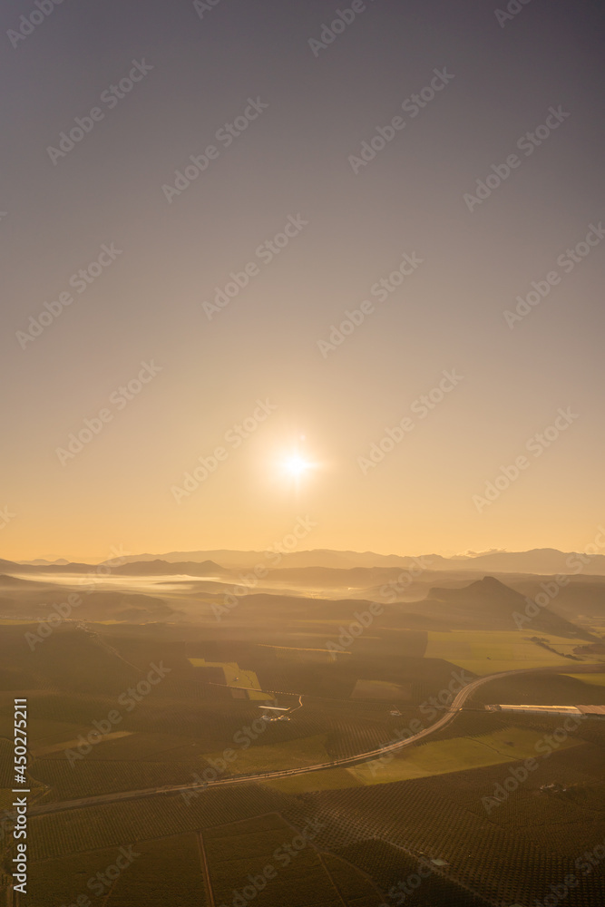 Obraz premium aerial view of sunrise in the countryside with light mist over the mountains and clear skies.