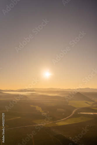 aerial view of sunrise in the countryside with light mist over the mountains and clear skies. © victor
