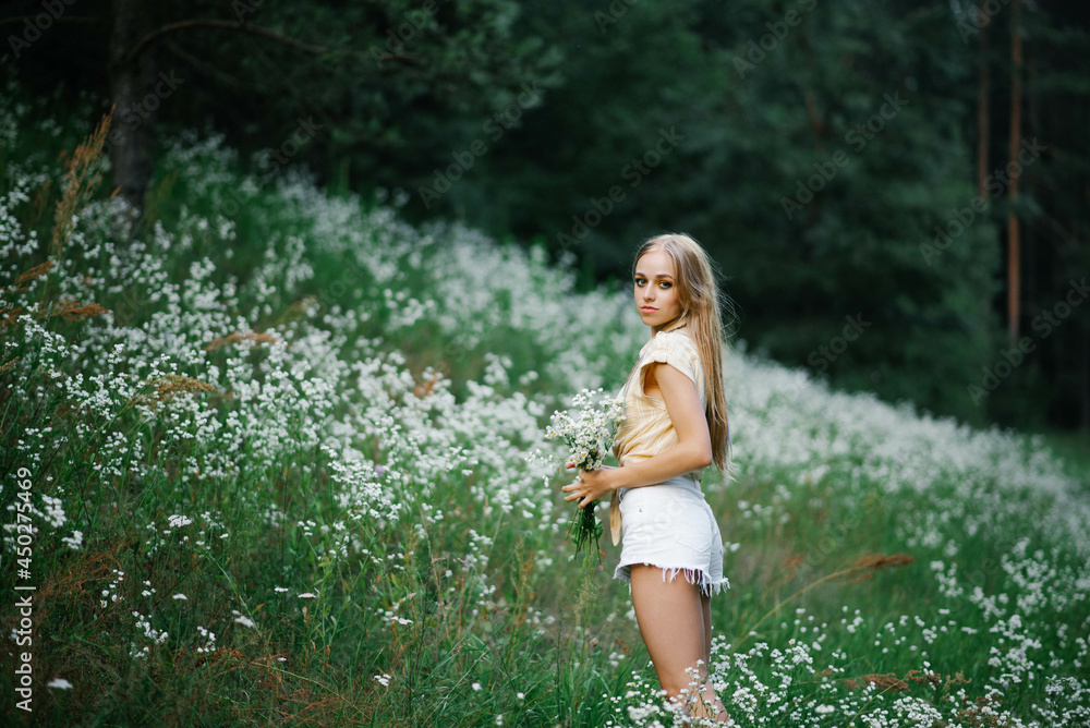 A girl in a field with flowers. Beautiful young woman in a field with white meadow flowers.