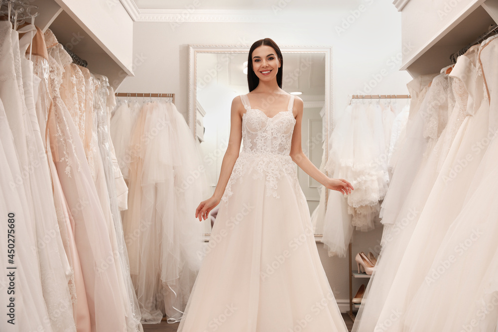 Woman trying on beautiful wedding dress in boutique Woman trying on beautiful wedding dress in boutique