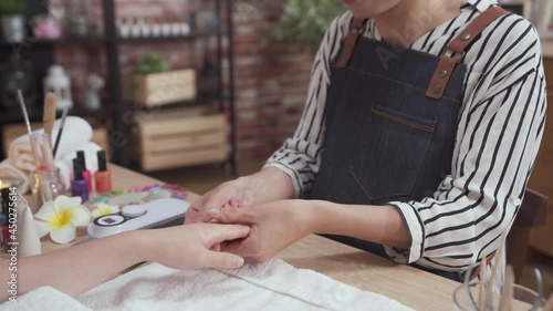 closeup view of two female hands while beautician massage spa customer hands skin with moisturizing lotion before nail polishing, therapist doing manicure on hand of young asian woman in spa salon.