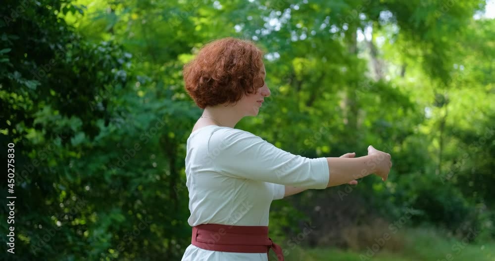 Female practicing qigong and meditation in summer park or forest Female practicing qigong and meditation in summer park or forest