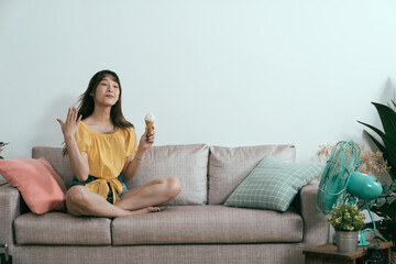 portrait of delightful taiwanese woman fanning herself while beating the heat and staying cool with gelato and electric fan. summer vacation concept