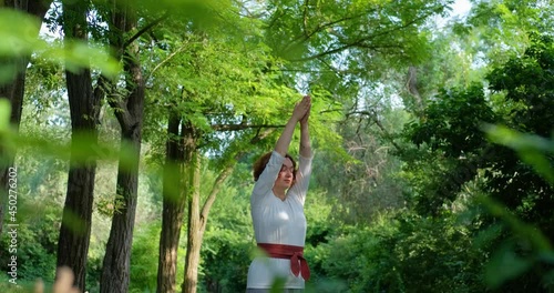 Female practicing qigong and meditation in summer park or forest