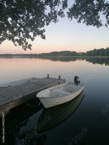 Small dingy boat in calm water with sunset reflection