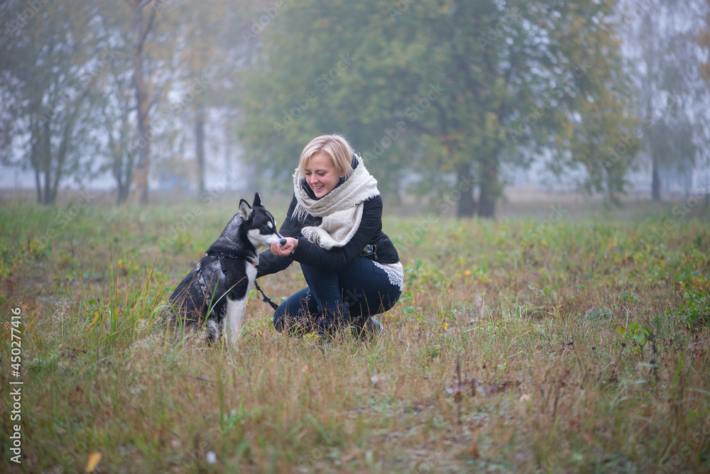 Young woman with beautiful siberian husky dog playing in city park during autumn Young woman with beautiful siberian husky dog playing in city park during autumn