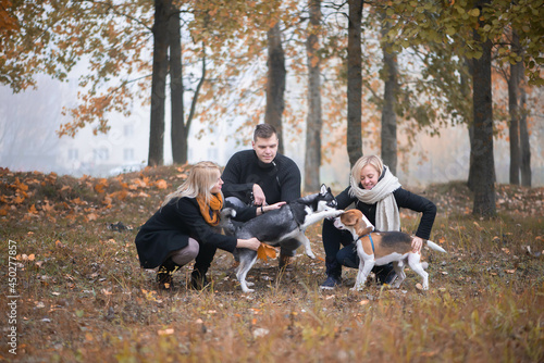 pet owners with siberian husky and beagle dogs have a nice time in the city park on an autumn morning © Zelma