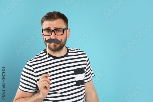 Funny man with fake mustache on turquoise background, space for text