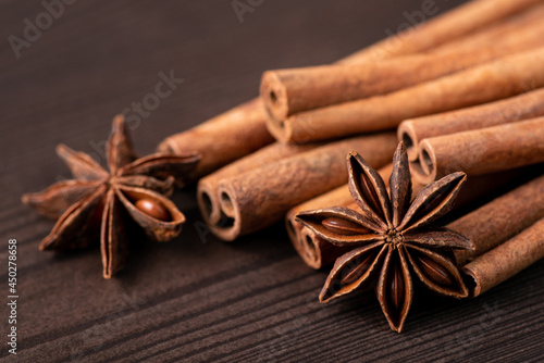 Cinnamon sticks and anise stars on wooden table. Bright photo of spices for bakery on dark background