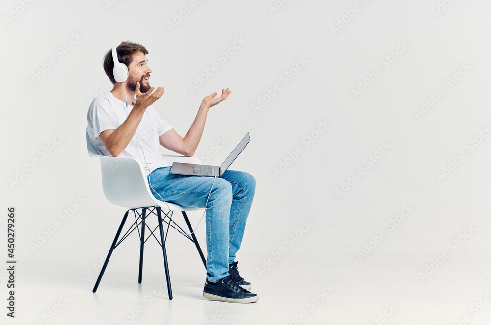 young man sitting on a chair with a laptop in headphones technology young man sitting on a chair with a laptop in headphones technology