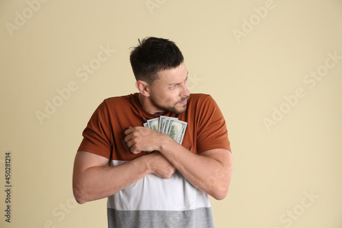 Greedy man hiding money on beige background photo