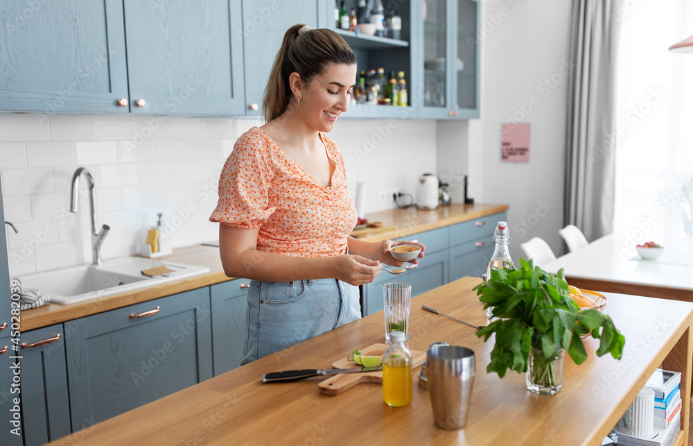 culinary, drinks and people concept - happy smiling young woman making lime mojito cocktail at home kitchen culinary, drinks and people concept - happy smiling young woman making lime mojito cocktail at home kitchen