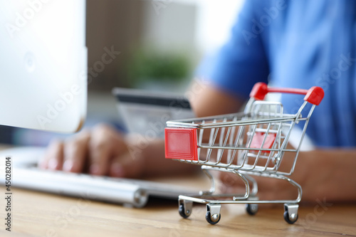 Female hand with keyboard and shopping trolley closeup