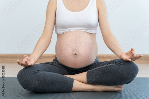 Pragnant woman practicing yoga at home. Young beautiful girl doing exercises at home. balance, meditation, relaxation, healthy lifestyle concept photo