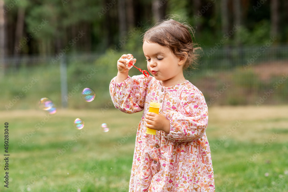 childhood, leisure and people concept - happy little baby girl blowing soap bubbles in summer