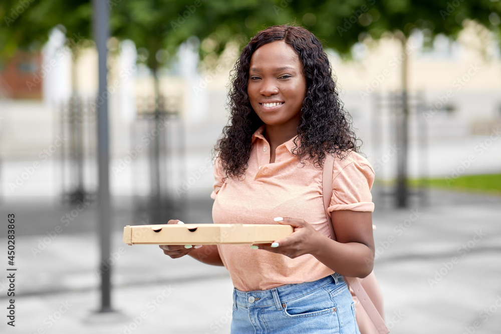 education, school and people concept - happy smiling african american student girl with takeaway pizza box on city street education, school and people concept - happy smiling african american student girl with takeaway pizza box on city street
