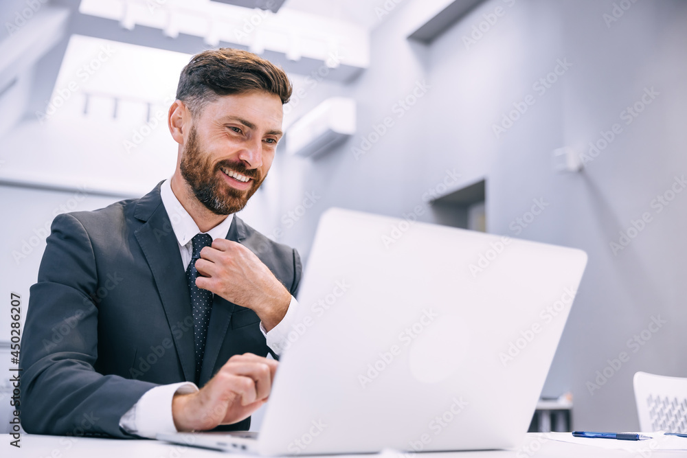 A young man works from home, makes documents, using a laptop straightens his tie. A young man works from home, makes documents, using a laptop straightens his tie.