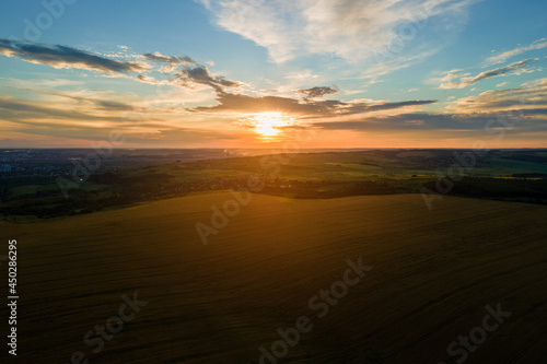 Aerial landscape view of yellow cultivated agricultural field with ripe wheat on vibrant summer evening.