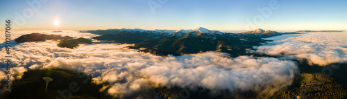 Aerial view of vibrant sunrise over white dense fog with distant dark Carpathian mountains on horizon.