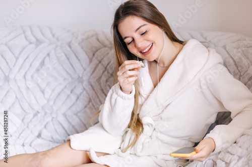 woman listen to music and eat on sofa in morning at home