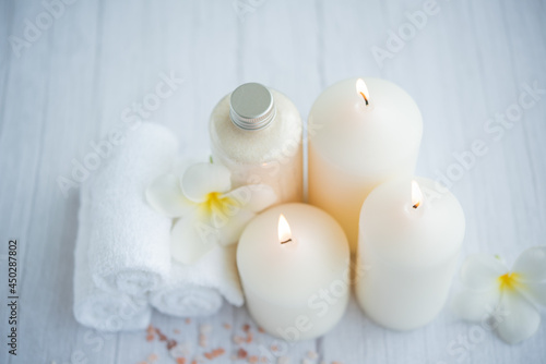 Spa coconut products on light wooden background. Composition with towels, flowers and salt, candle on massage table in spa salon
