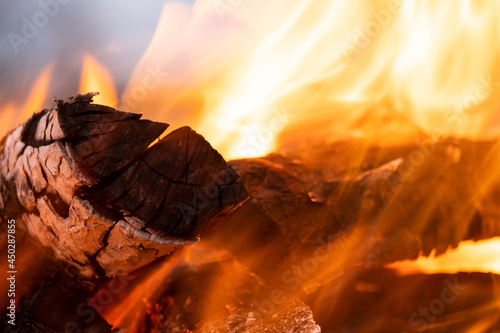 Close up of brightly burning wooden logs with yellow hot flames of fire at night.