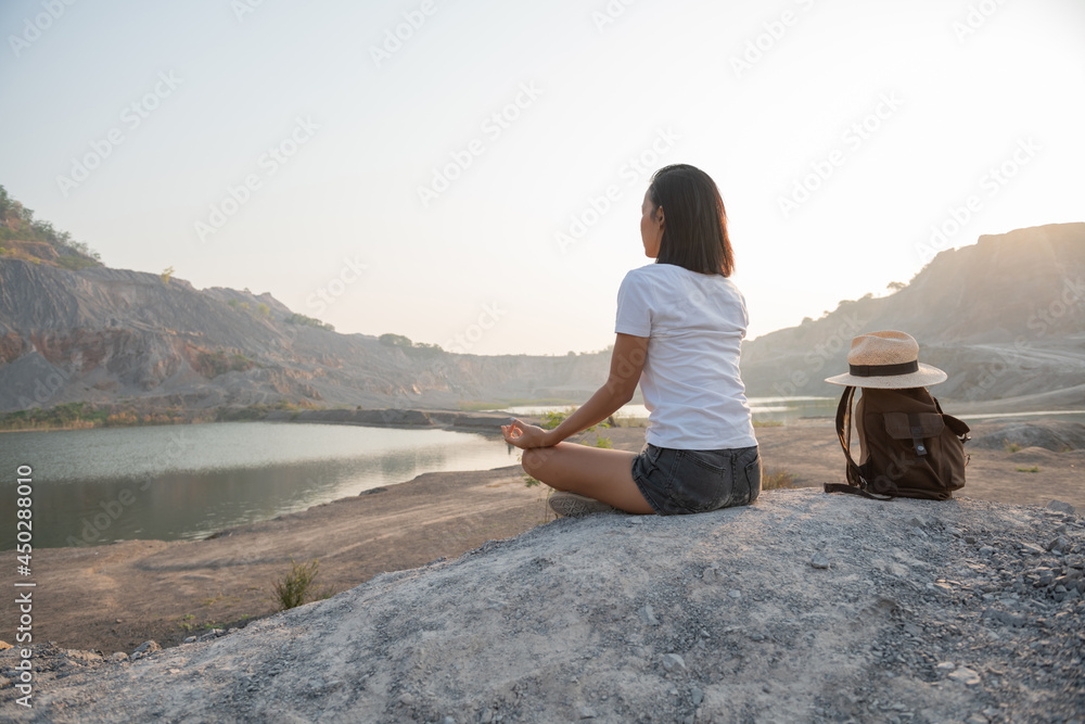Unity with nature. young woman doing meditating outdoors near lake or river at sunset, sitting in lotus pose and meditating on the background of nature. healthy lifestyle and yoga concept.