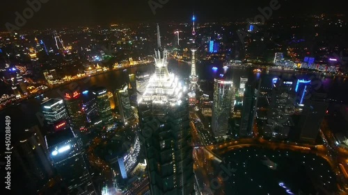 Elevated view of high-rise buildings with river at night in Shanghai;China.Jin Mao Tower(one of China's tallest buildings) and Oriental Pearl Tower;busy shipping & urban traffic;time lapse.  photo
