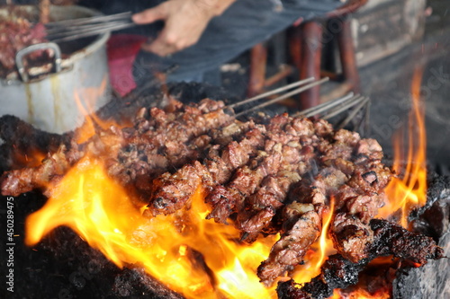 sate kambing or satay goat, lamb, Lamb or meat goat satay with charcoal  ingredient on red fire grilling by people. traditional satay from yogyakarta, java, Indonesia 

cooking satay photo