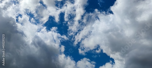 Light gray clouds on the blue sky. Several clouds merge into a cloud, from below the gray clouds from above are white. They cover almost the entire sky, through small gaps you can see the blue sky.