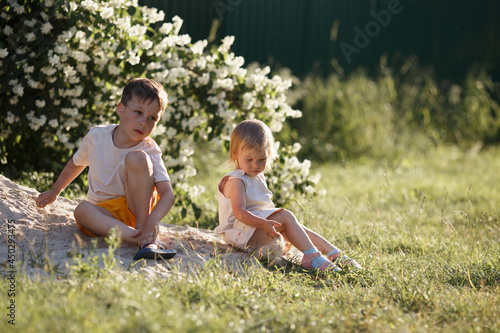 the older brother and his younger sister throw sand on the grass