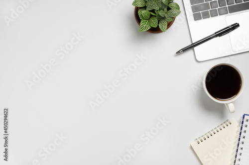 White desk  with Laptop, blank notepad, flower, coffee cup and pen. Flat lay top view copy space.