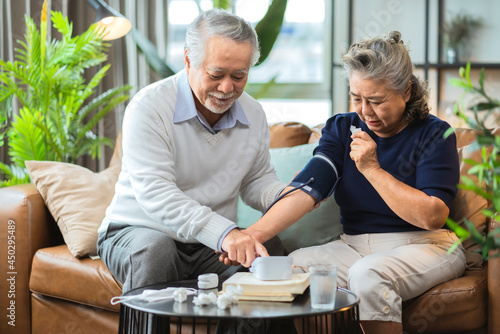 grandfather hand use digital Measuring blood pressure at home with portable device checking for grandmother,asian couple checking blood pressure at home.