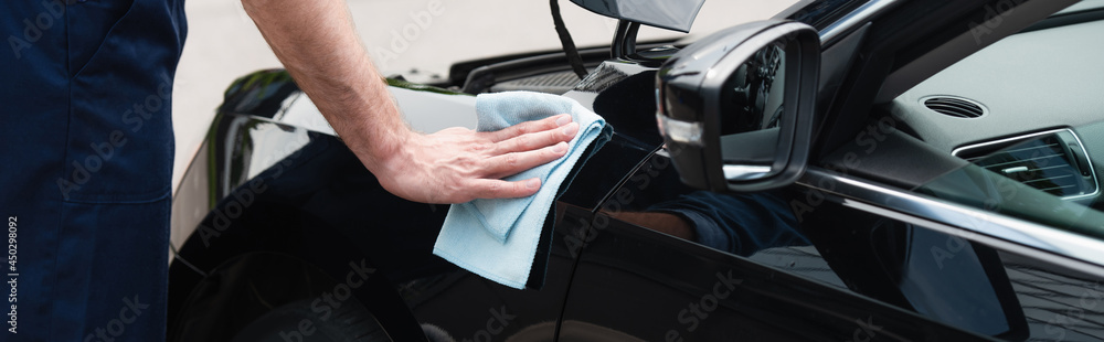 Cropped view of mechanic cleaning car with rag, banner