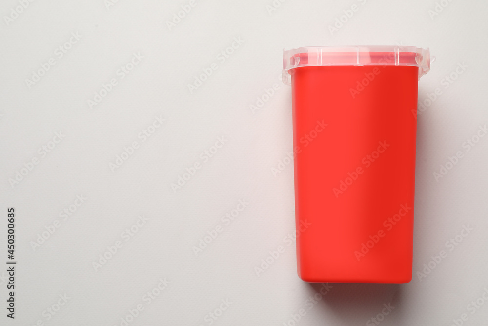 Sharps container for used syringe on light background, top view. Space for text Sharps container for used syringe on light background, top view. Space for text