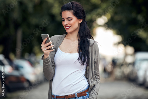 Young cute female using smartphone on the street.