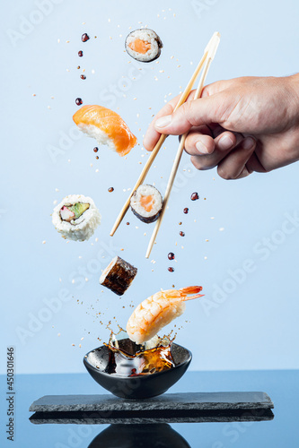 Flying pieces of sushi on blue background.  Vertical format.
