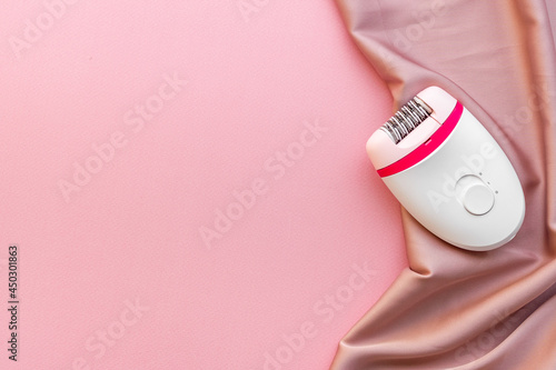 White epilator on soft silk. Hair removal and depilatory concept photo