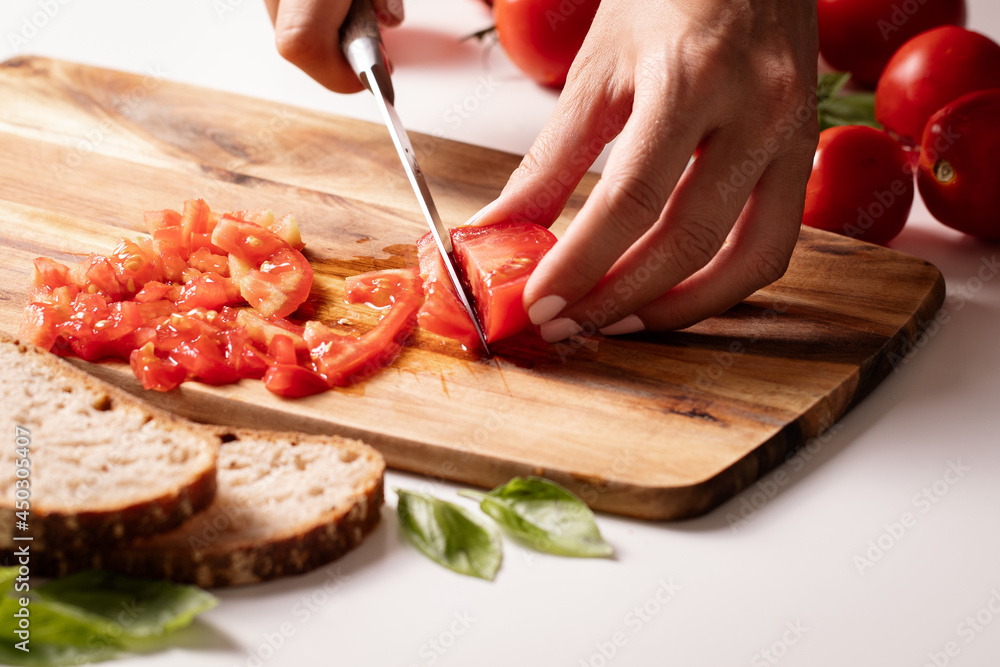 Cutting fresh tomato and preparng homemade bruschetta with olive oil, garlic and basil Cutting fresh tomato and preparng homemade bruschetta with olive oil, garlic and basil