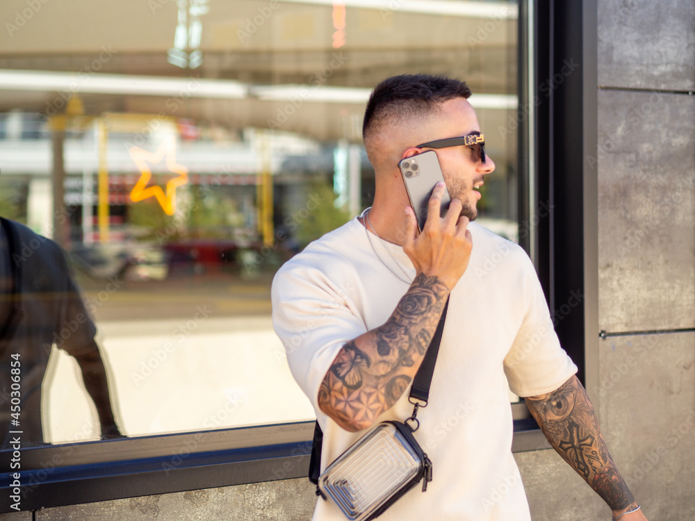 Hombre joven con tatuajes hablando por teléfono 