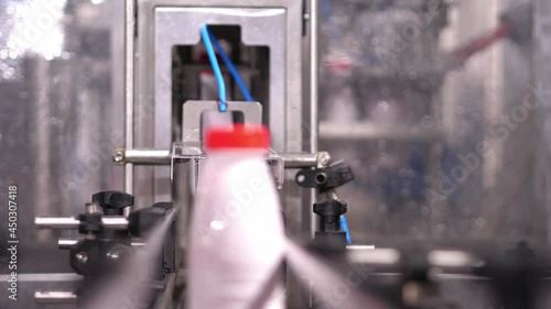 Sliding filled plastic bottle with a red lid along the conveyor line and slowly continuing the movement.