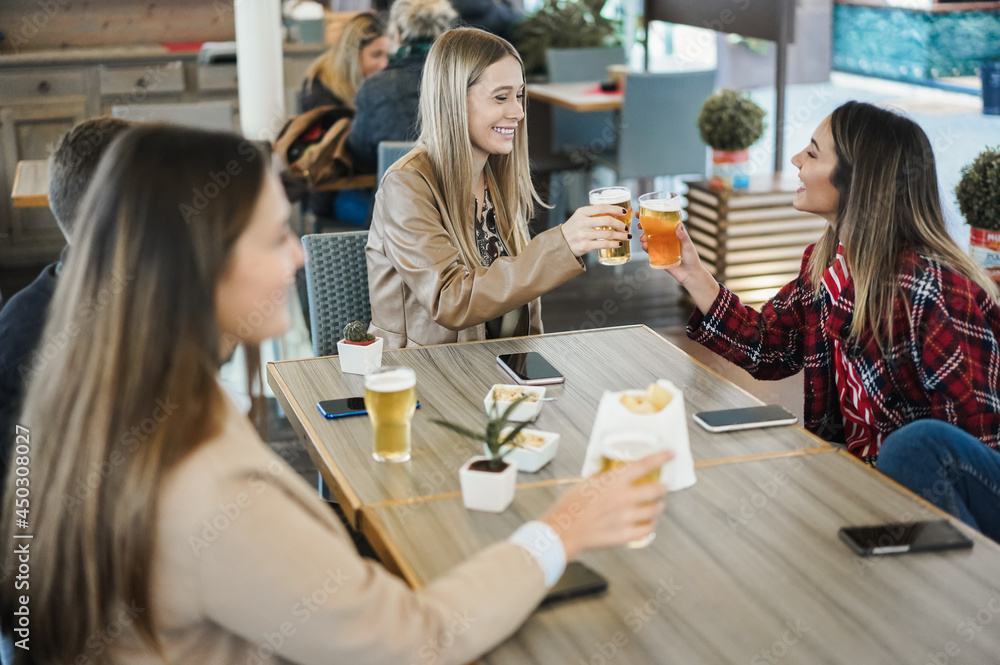 Young friends having fun clinking with beer inside bar restaurant - Focus on center girl face Young friends having fun clinking with beer inside bar restaurant - Focus on center girl face