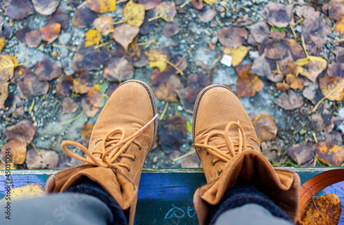 light brown boots on background of colorful autumn leaves