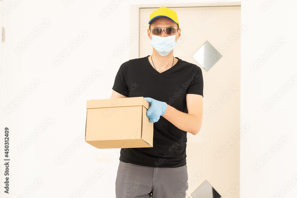 Delivery man holding cardboard boxes in medical rubber gloves and mask. copy space. Fast and free Delivery. Online shopping and Express delivery. Quarantine Delivery man holding cardboard boxes in medical rubber gloves and mask. copy space. Fast and free Delivery. Online shopping and Express delivery. Quarantine