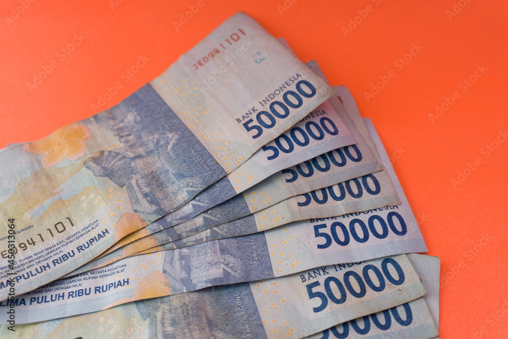 Obraz premium The Indonesian currency is rupiah, which is very much scattered and is worth fifty hundred thousand rupiah. Isolated in orange. For illustrations of news with the theme of economy, buying sell.