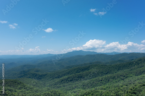 Forest covered foothills of the Blue Ridge Mountains on North Carolina, NC, USA with brilliant blue sky and puffy white clouds