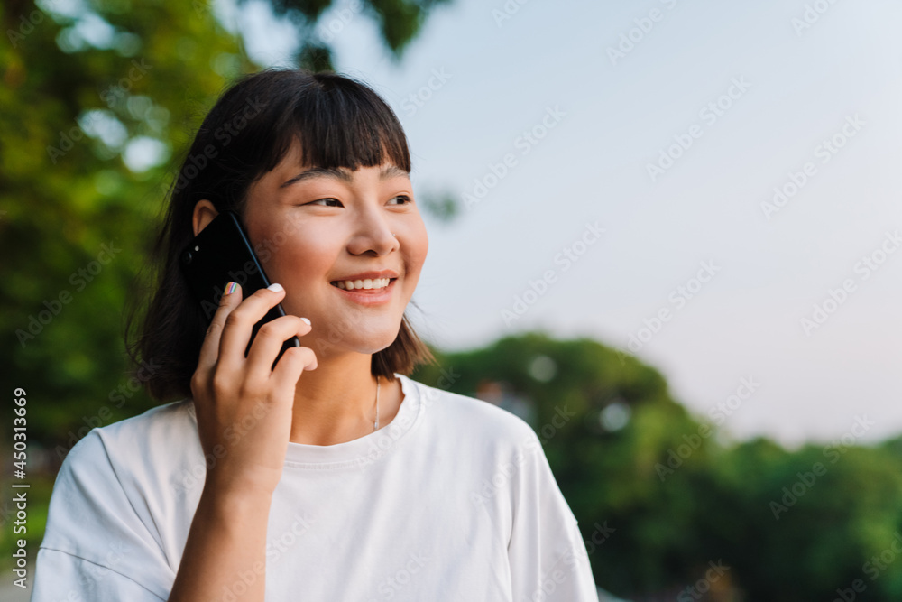 Smiling young asian woman walking in a green park Smiling young asian woman walking in a green park