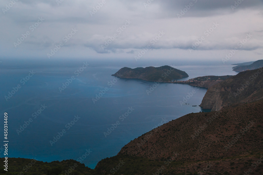 Top view at Asos village and Assos peninsula during bad weather conditions, thunderstorm and rain, with low dark clouds and visible currents at sea. Cephalonia, Greece.